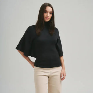 Black turtleneck half-sleeve sweater with flared batwing sleeves, paired with beige trousers.