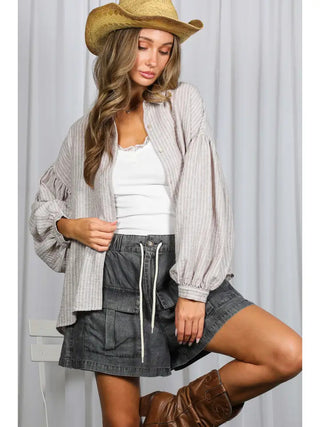 Oversized striped linen shirt with long balloon sleeves and button-front closure in beige and white tones.