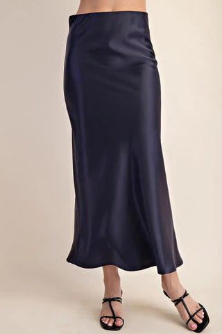 Navy blue satin midi skirt with elastic waistband, flowing silhouette, paired with black strappy heels.
