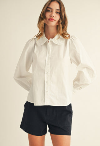 White ruffle collar button-down shirt with puffed long sleeves and delicate button front closure.
