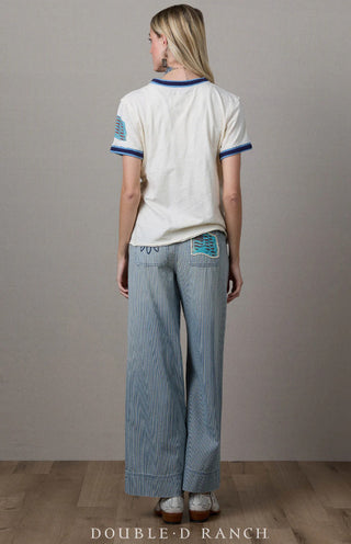 White short-sleeve tee with blue trim at collar and cuffs, featuring turquoise embroidered patch detail on back.