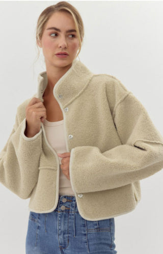 Sherpa cropped jacket with high neckline, soft faux suede on the other, and finished with jumbo snap buttons, and seam allowance out-line detailing.
