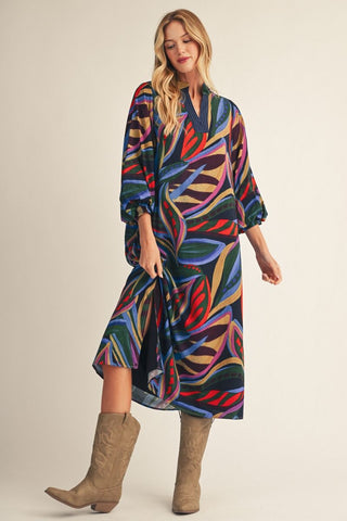 Colorful abstract floral midi dress with 3/4 puff sleeves, V-neckline, worn with tan cowboy boots.