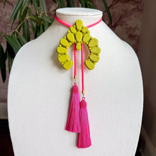 Olive green naja pendant bolo necklace with neon pink cord and dual fuchsia silk tassels on display bust.
