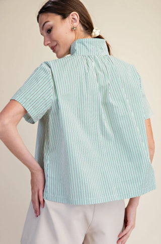 Woman wearing a mint green and white striped short sleeve shirt with a stand collar, back view.