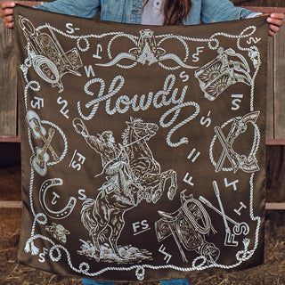 Brown bandana with white Western illustrations: cowboy on rearing horse, "Howdy" script, guitars, guns, saddle, rope border.