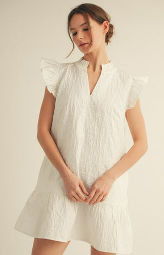 White textured floral mini dress with ruffled cap sleeves and V-neckline on female model.
