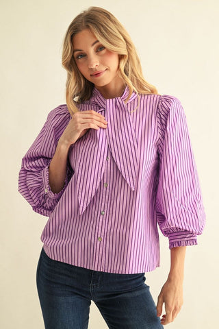 Purple striped button-down blouse with puff sleeves, ruffled cuffs, and elegant tie neck detail.