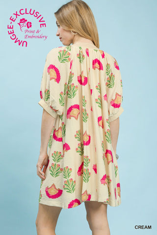 Cream mini dress with pink and green floral block print, short cuffed sleeves, back view.