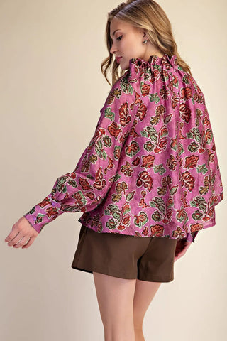 Magenta floral print ruffle neck blouse with long sleeves, oversized silhouette, paired with olive shorts.