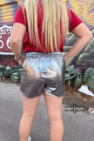 Marfa Metallic Shorts in silver, worn with red tee, featuring elastic waistband and shiny finish.