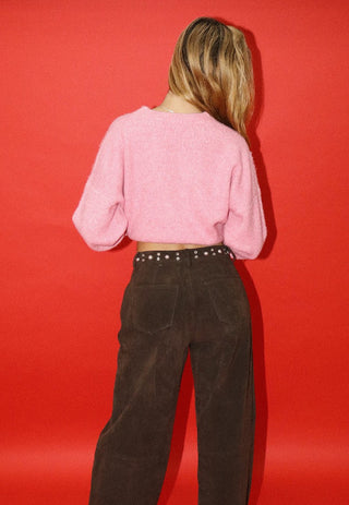 Pink fluffy cropped knit sweater with balloon sleeves, worn with brown corduroy pants and studded belt.
