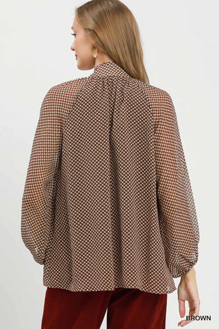 Brown polka dot print long sleeve blouse with tie neck and billowy silhouette, back view.