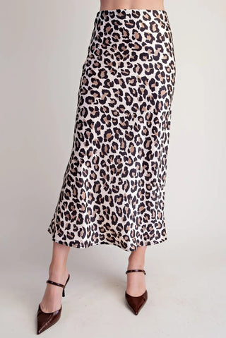 Ivory and black leopard print satin midi skirt with high waist, styled with dark brown pointed-toe heels.