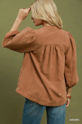 Brown sueded split neck blouse with contrast stitching, puff sleeves, and gathered back detail.