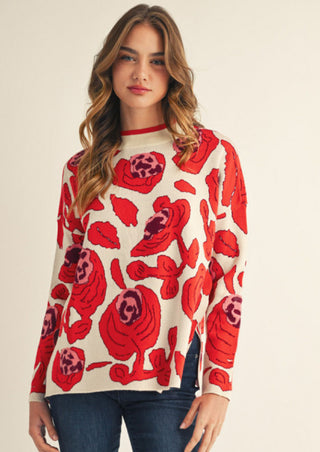 White drop shoulder sweater with bold red and pink oversized floral pattern, long sleeves, crew neck.