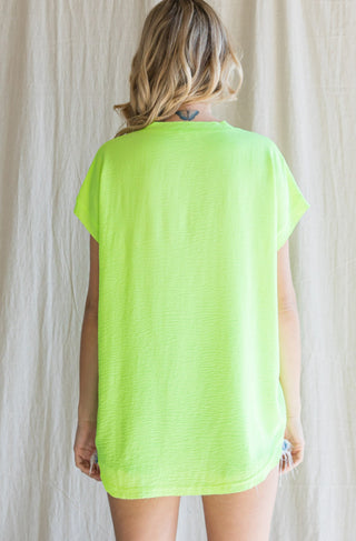 Neon lime green oversized cap sleeve top with raw edge hems, shown from back view.