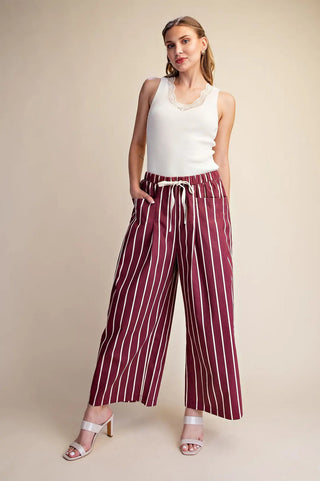 Burgundy and white striped wide-leg pants with drawstring waist, paired with white lace tank top and heeled sandals.