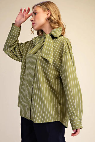 Olive green pinstripe long-sleeve blouse with elegant neck bow tie detail, paired with navy trousers.