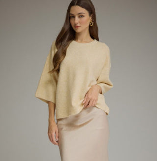 Beige knit sweater with ¾ sleeves, round neckline, and ribbed trim, styled over a satin skirt.