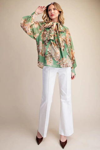 Green floral chiffon blouse with bow tie neck, long sleeves, paired with white wide-leg trousers.