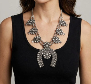 Silver squash blossom statement necklace with floral concho pendants and horseshoe-shaped naja centerpiece on model.