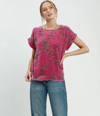 Pink floral velvet boxy short-sleeve top with dark botanical print, paired with blue jeans.
