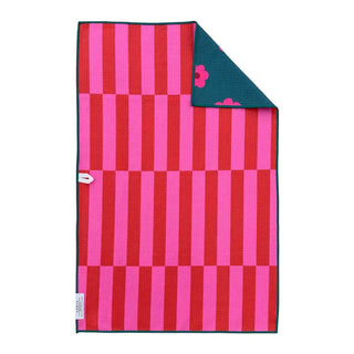 Reversible hand towel with bold pink and red stripes, teal back featuring pink floral print, green edges.