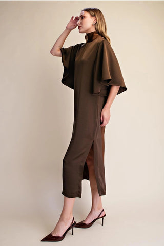 Chocolate brown satin midi dress with flowy cape sleeves, mock neck, and front slit, styled with burgundy heels.