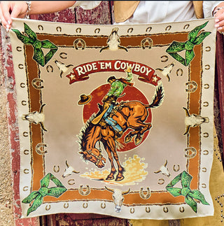 Brown western bandana featuring a rodeo cowboy on bucking horse, horseshoes, bull skulls, and green bow corners.