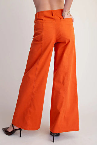 Orange wide leg pants with seam stitching detail, worn with black heels, back view shown.