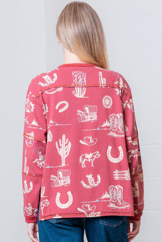 Red western print long sleeve top with cowboy boots, cactus, horseshoe, and wagon graphic pattern.