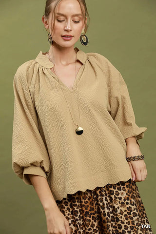 Tan textured split V-neck blouse with balloon sleeves and scalloped hem, styled with leopard skirt.