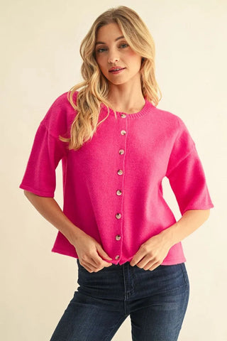 Hot pink drop shoulder short sleeve button-front sweater cardigan paired with dark wash jeans.