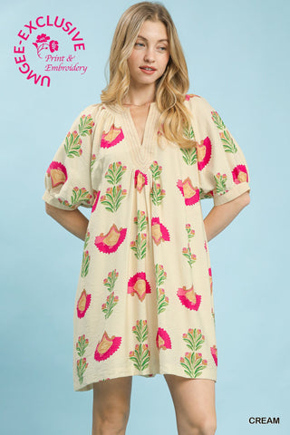 Cream mini dress with pink and green floral block print, V-neckline, and puffed short sleeves.