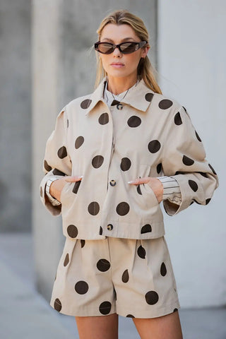 Beige cropped jacket with large dark brown polka dots, collar neckline, and button front closure.