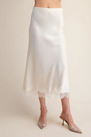 White satin midi skirt with delicate lace hem trim, styled with crystal embellished slingback heels.