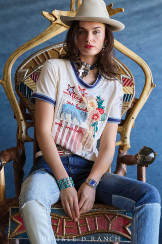 White graphic tee with patriotic embroidery reading "one flag, one land, one nation" with floral and star details, blue ringe