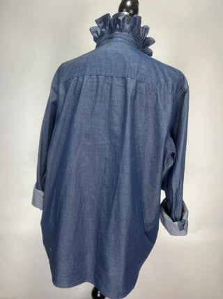 Blue chambray women's shirt with ruffled collar, rolled cuffs, relaxed fit, shown from back view.