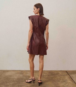 Burgundy vegan leather sleeveless mini dress with structured shoulders, fitted silhouette, and back zipper closure.