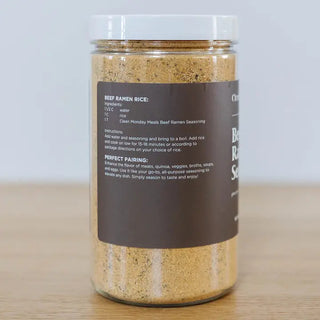 Clear glass jar filled with brown beef ramen seasoning powder, featuring a dark brown label with recipe instructions.