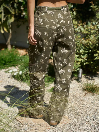 Olive green wide-leg barrel pants featuring allover white western cowboy and horse rodeo print pattern.