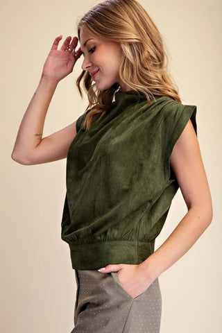 Olive green sleeveless suede mock neck top with elastic waistband, paired with gray dotted pants.