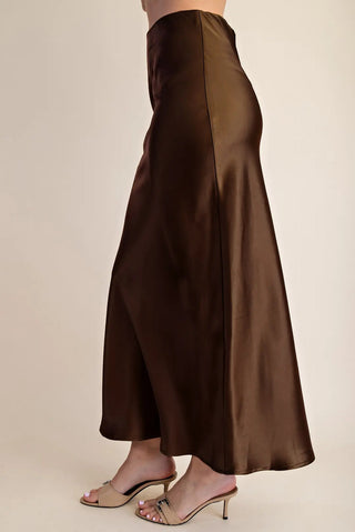 Chocolate brown satin midi skirt with elastic waistband, A-line silhouette, paired with nude heeled mules.