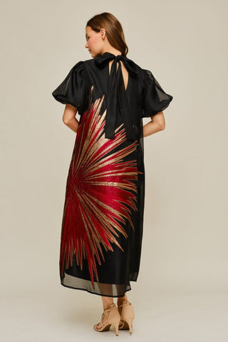 Black midi dress with red and gold metallic starburst embroidery, puff sleeves, and tie-back high neck detail.