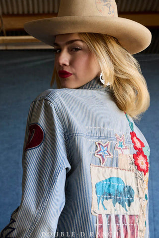Woman wearing blue striped denim jacket with embroidered patches featuring buffalo, stars, and red floral details.