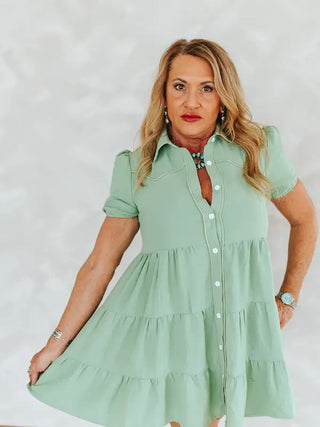 Pistachio green tiered ruffle dress with puff sleeves, button front, and western-style collar detailing.
