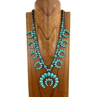 Turquoise and silver Navajo pearl squash blossom beaded necklace displayed on wooden bust, 24 inches.