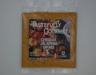 Clear packet of Tastefully Gourmet Cheddar Jalapeño Dip Mix showing golden-brown spice blend inside, 12 servings, 24g.