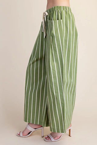 Green and white striped wide leg pants with drawstring waist, side pocket, worn with white heeled sandals.